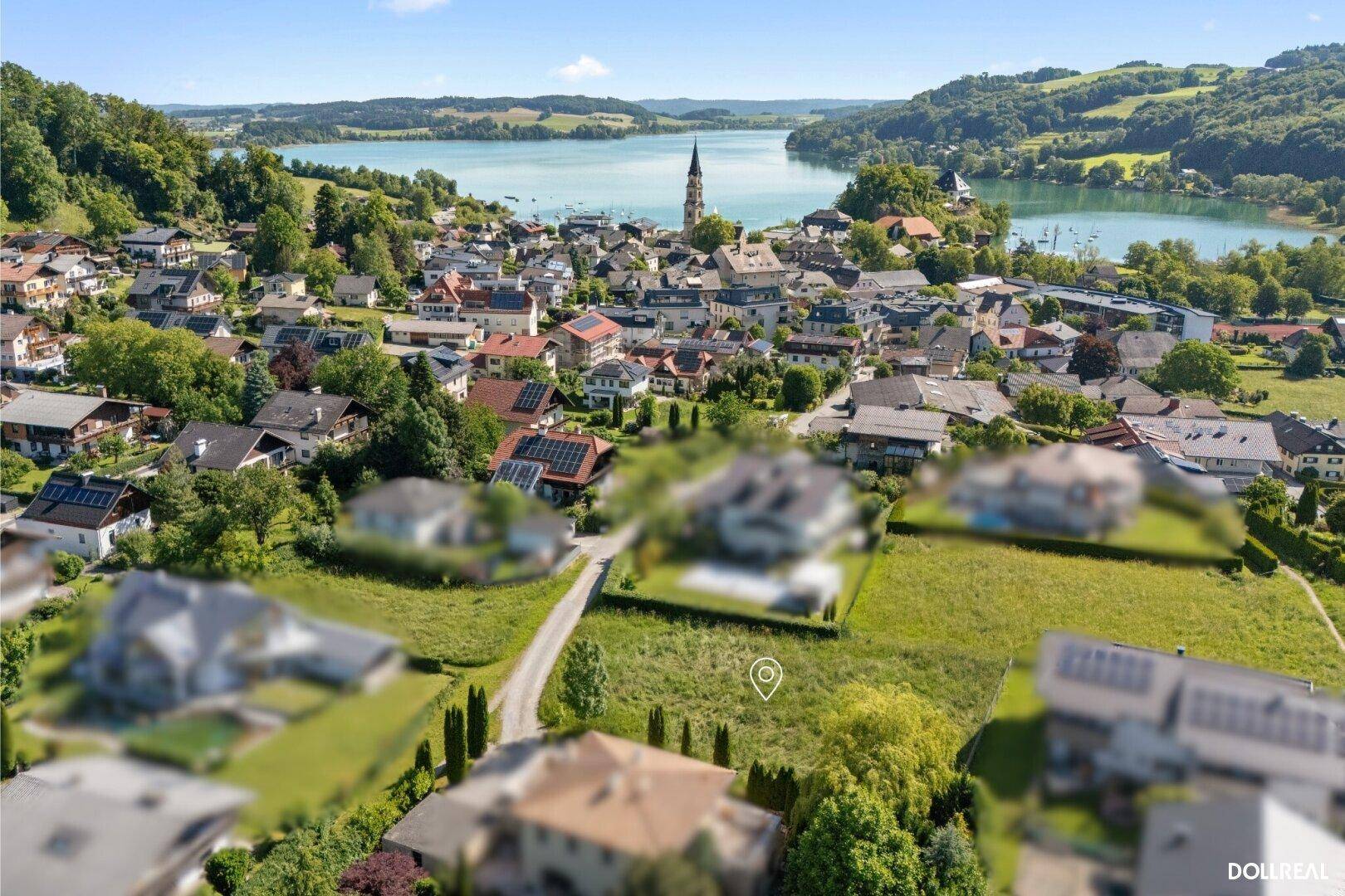 Luftaufnahme eines Baugrundstücks mit malerischem Seeblick und umliegender Dorfidylle.