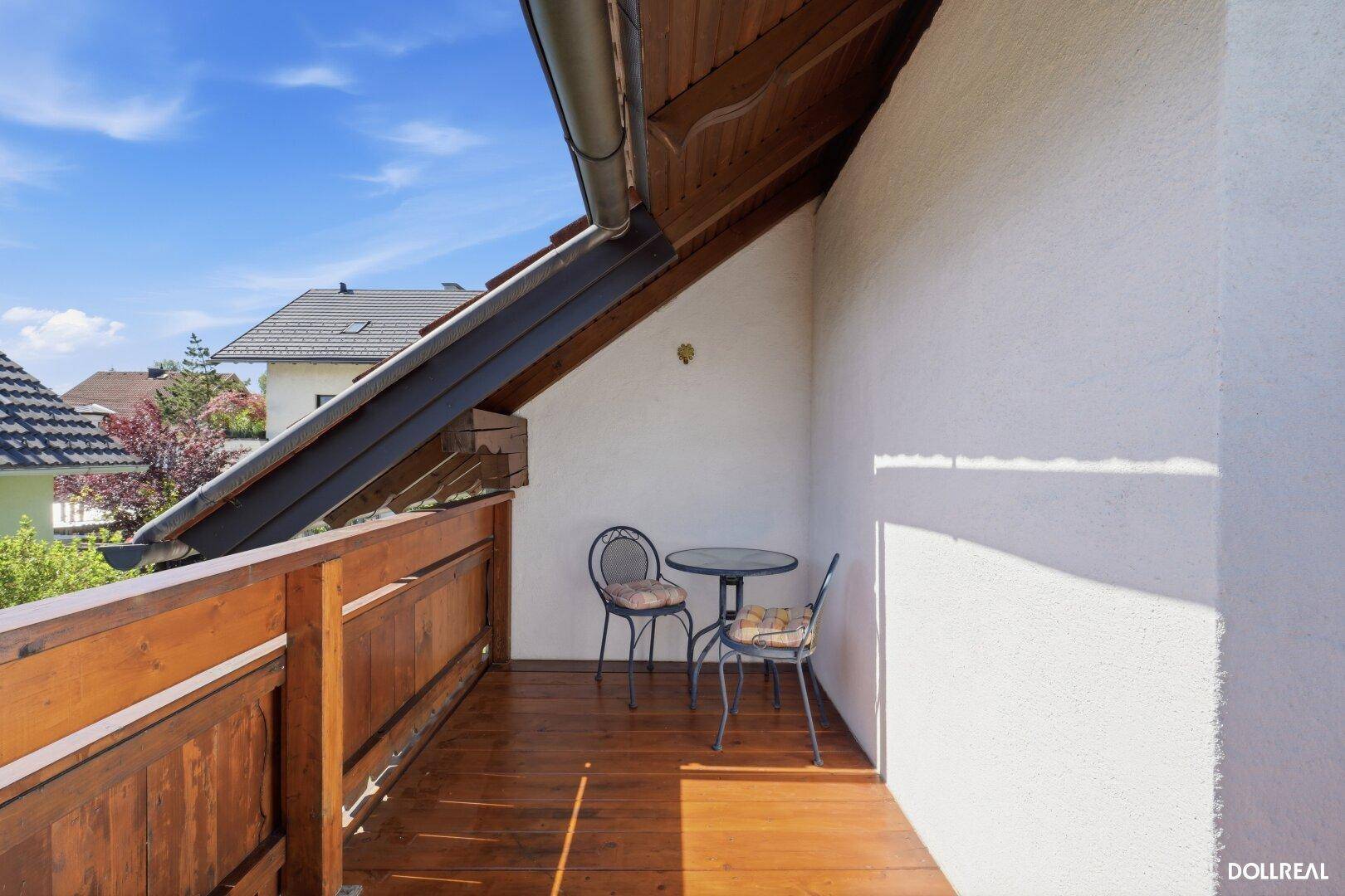 Sonniger Holzbalkon mit kleinem Tisch und Stühlen, ideal für entspannte Stunden im Freien.