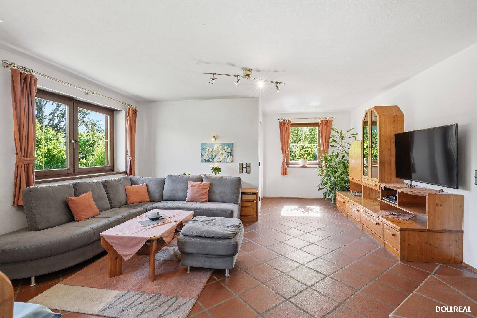 Geräumiges Wohnzimmer mit großem Ecksofa, Terrakotta-Fliesen und Blick in den Garten.
