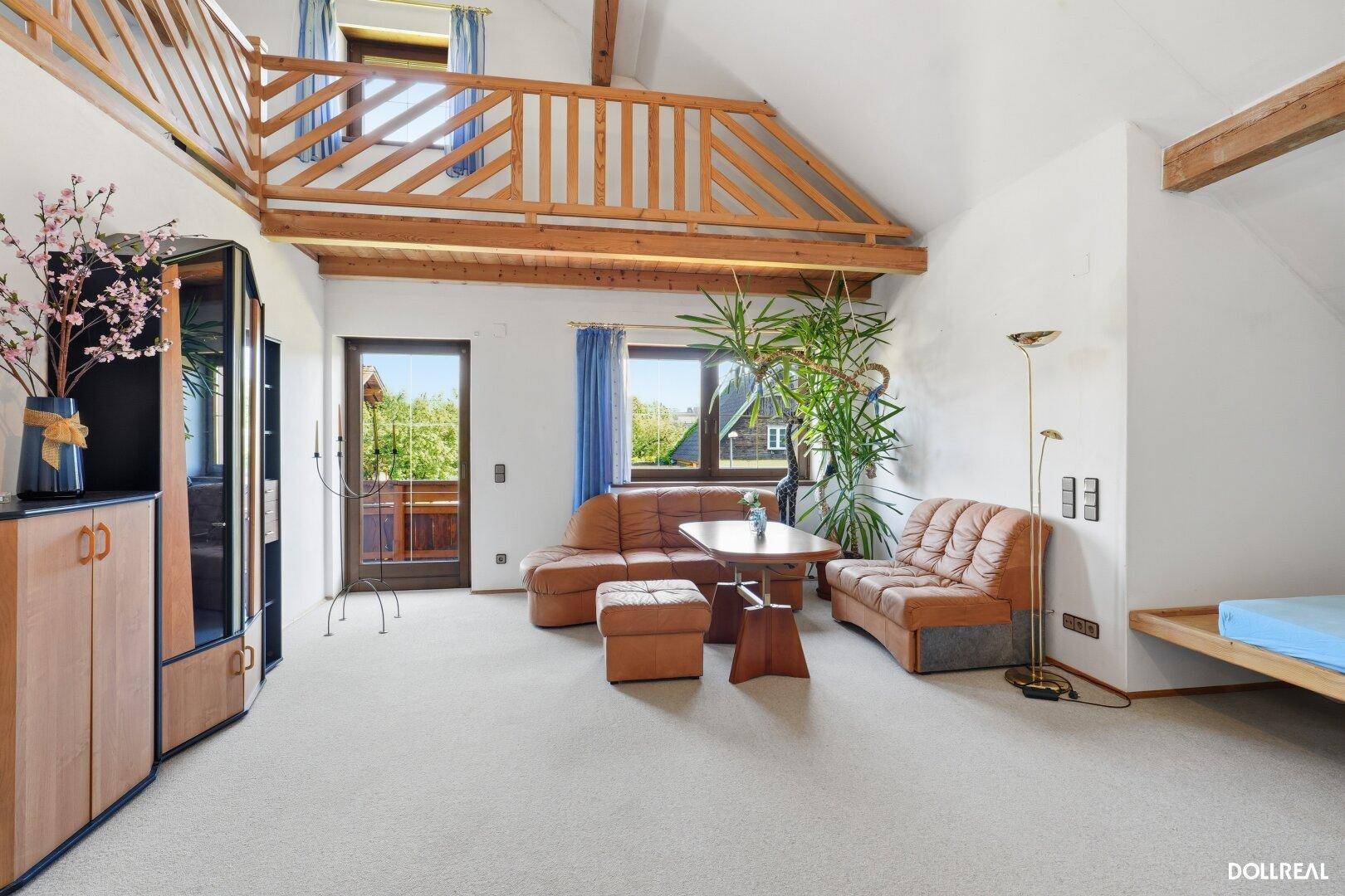 Offener Wohnbereich im Obergeschoss mit Galerie, hohen Decken und Zugang zum Balkon.