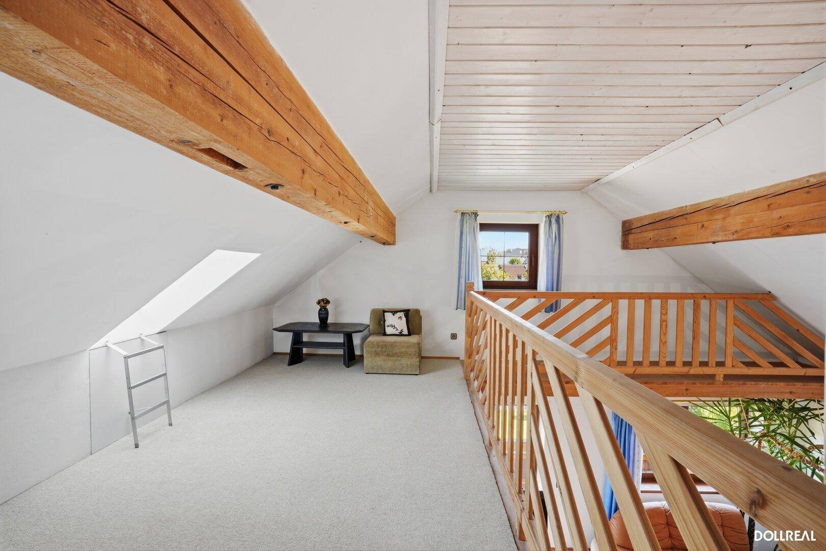 Helle Galerie im Dachgeschoss mit sichtbaren Holzbalken und Teppichboden.
