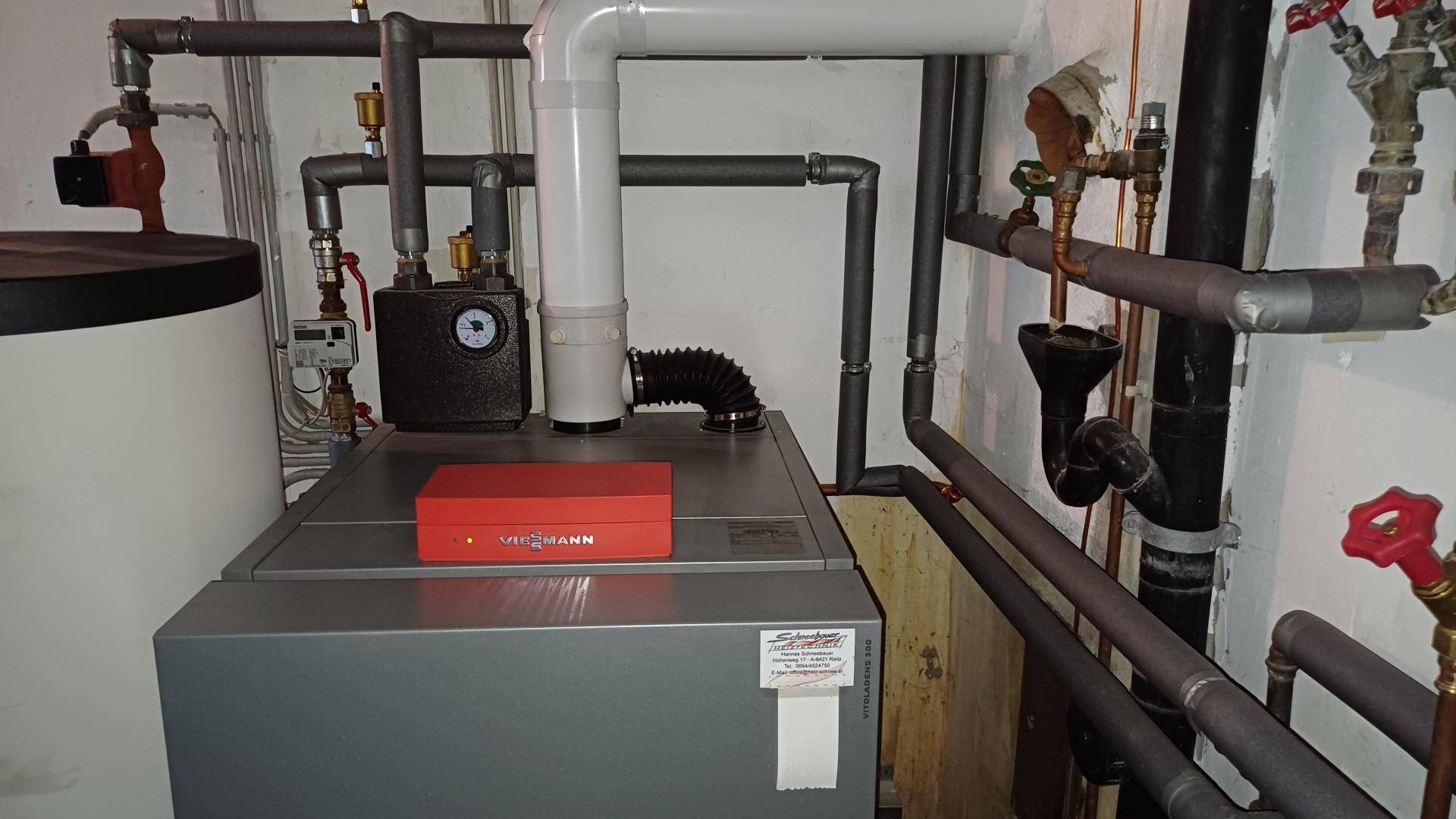Heizungsanlage mit Warmwasserspeicher und komplexer Rohrführung in einem Technikraum.