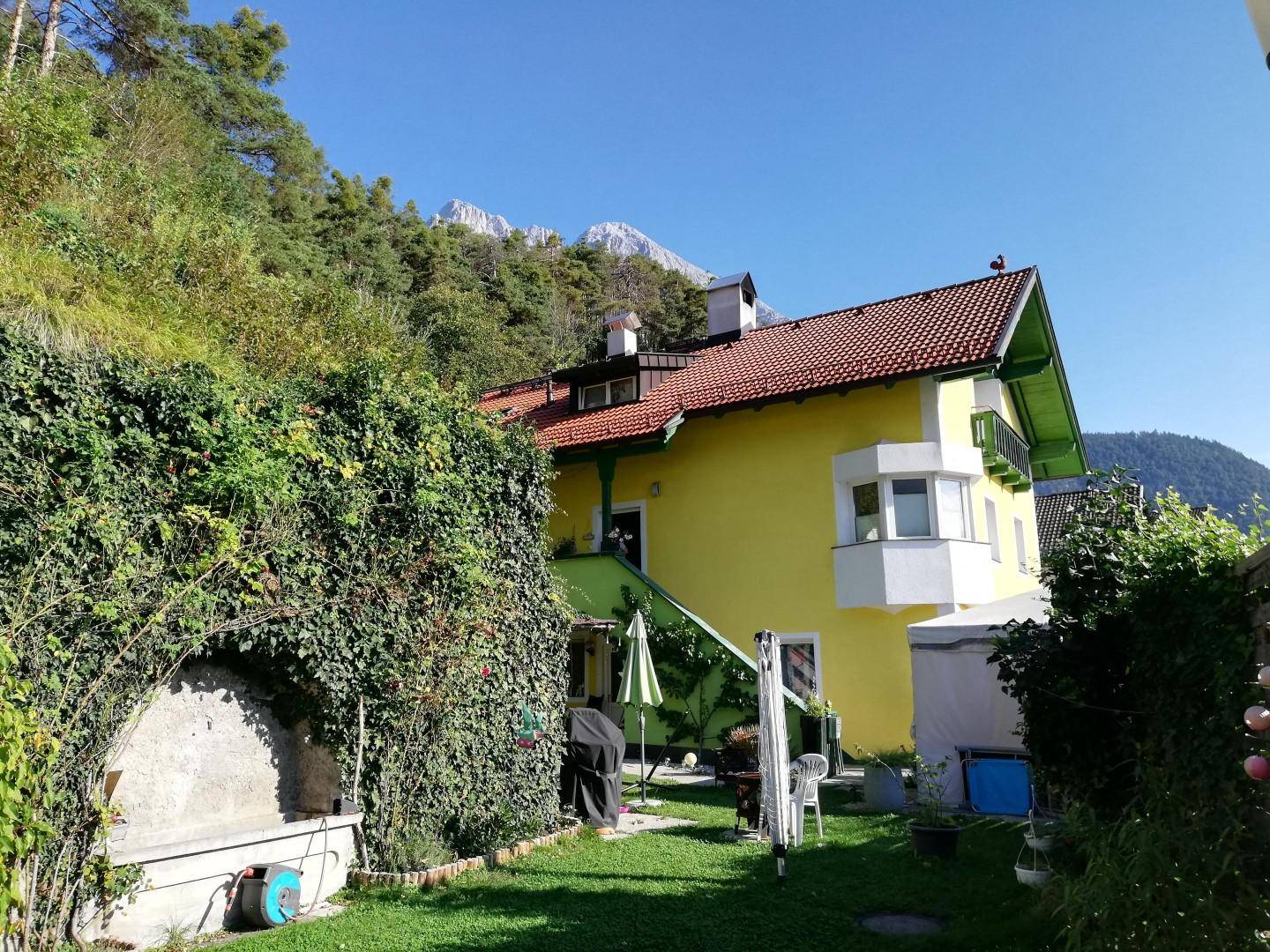 Hinterhofgarten mit Sitzgelegenheiten, Grillbereich und weitem Blick auf die Berge.