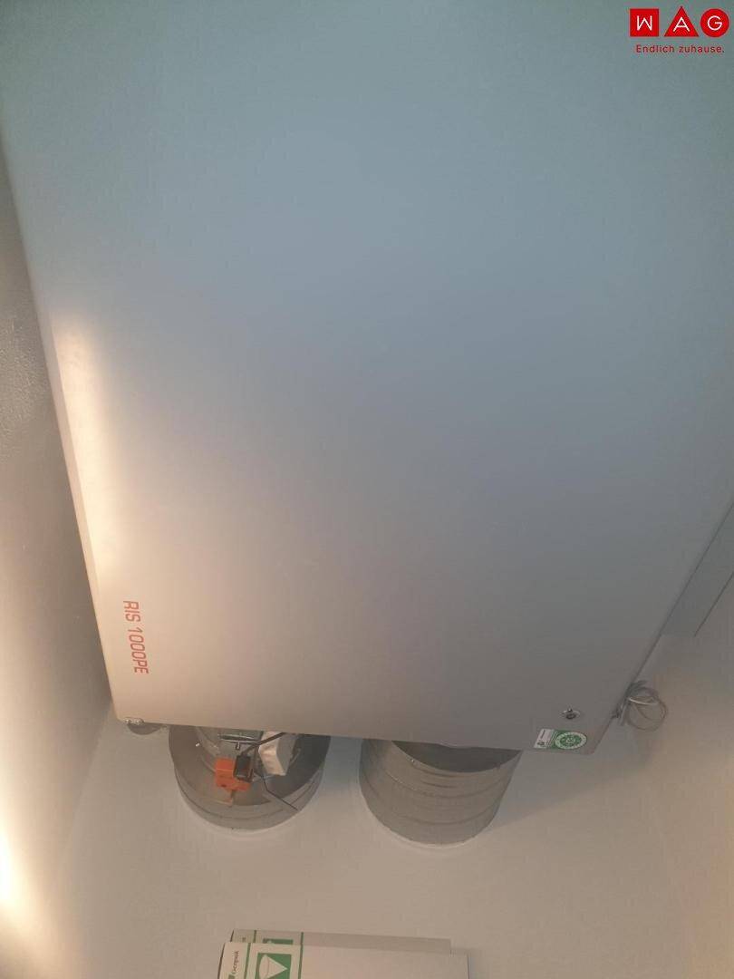 Deckenmontierte Lüftungsanlage mit sichtbaren Rohren in einem Innenraum.