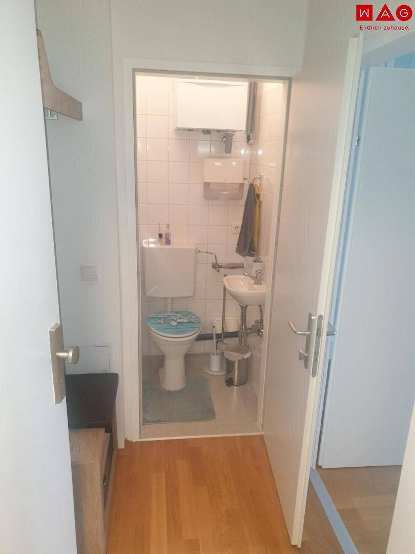Kleines WC mit Waschbecken, Toilette und Fliesen an den Wänden.