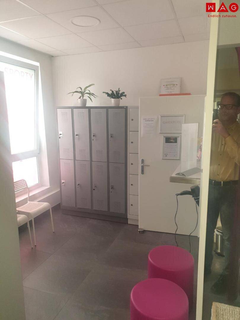 Umkleideraum mit Spinden, Fenster und pinken Hockern.