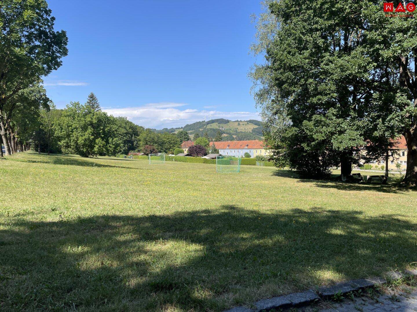 Weitläufige grüne Wiese mit kleinen Fußballtoren und Blick auf die umliegende Landschaft.