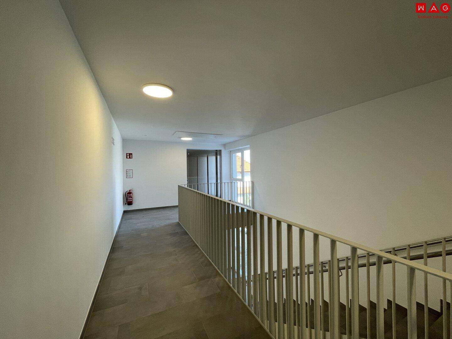 Helles Treppenhaus mit modernem Geländer und Fliesenboden, das die verschiedenen Etagen verbindet.