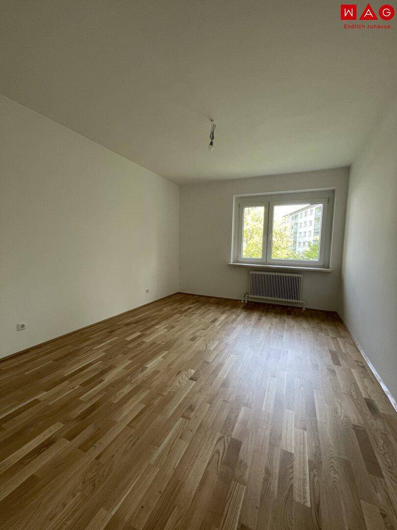 Helles, leeres Zimmer mit Parkettboden und Fenster, bereit zur individuellen Gestaltung.