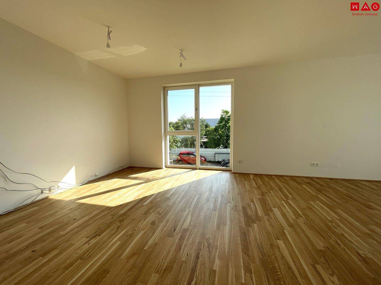 Heller, unmöblierter Raum mit Holzboden und großem Fenster.