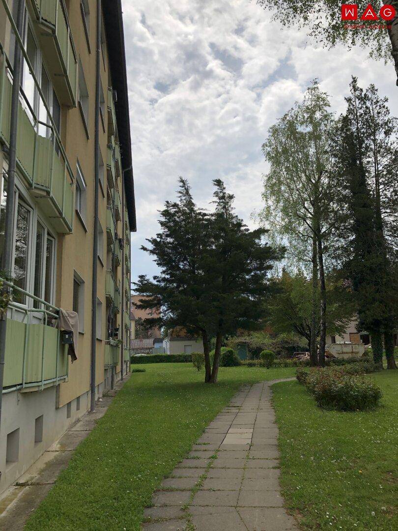 Seitenansicht des Gebäudes mit Balkonen und einem gepflegten Gartenweg.