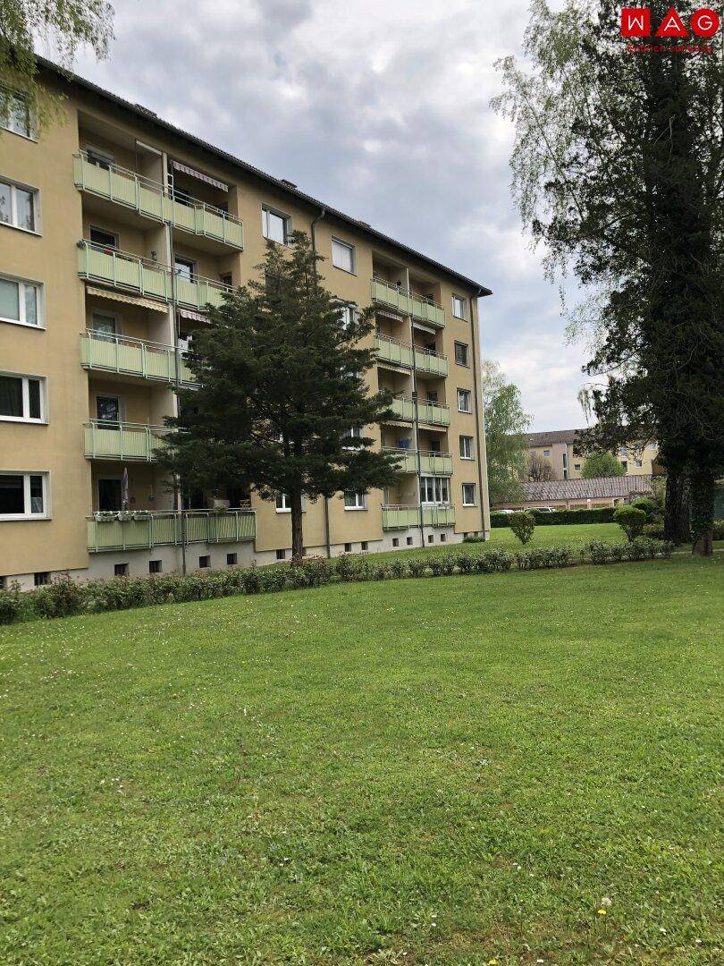 Ansicht des Mehrfamilienhauses mit mehreren Balkonen und großzügiger Grünfläche.