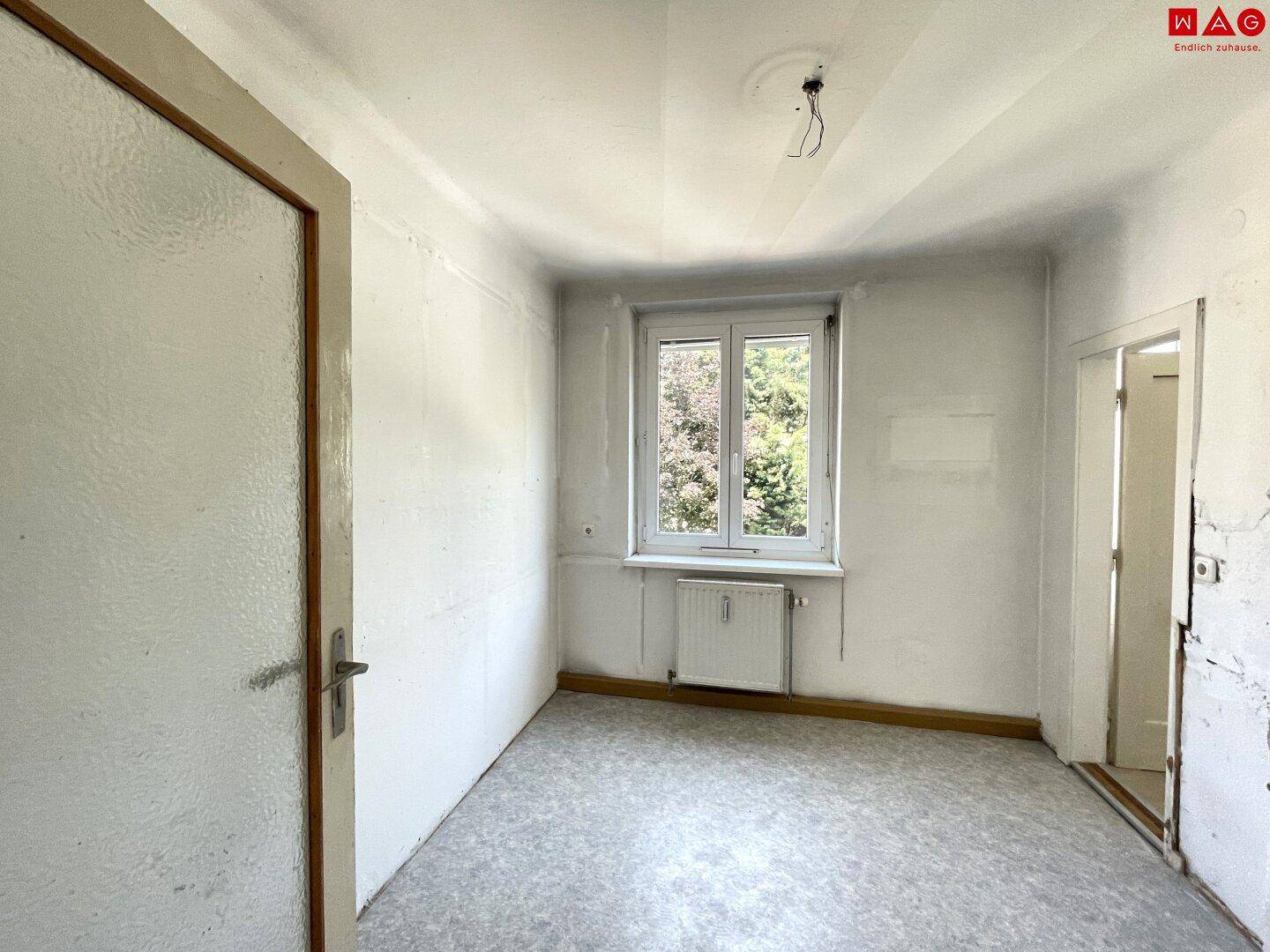 Zimmer mit Renovierungsbedarf, ausgestattet mit einem Fenster und Blick ins Grüne.