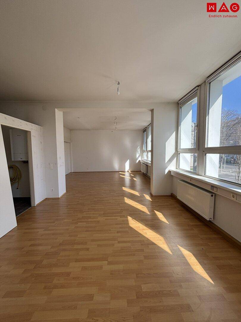 Geräumiger, leerer Raum mit Holzfußboden und großen Fenstern, bereit für die individuelle Gestaltung.