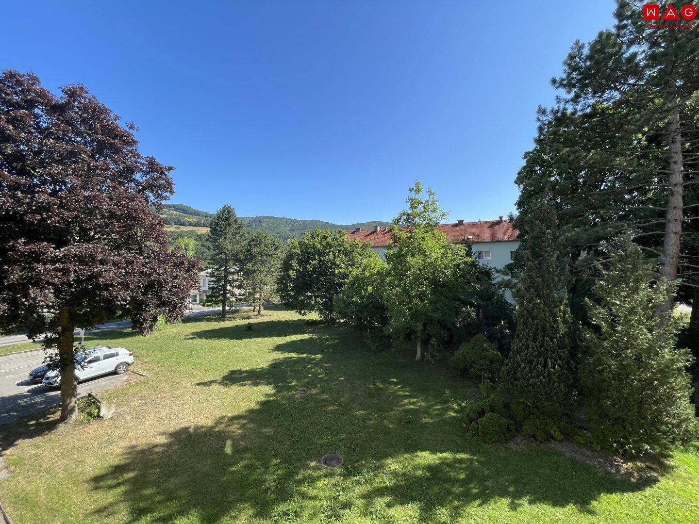 Weitläufige Grünfläche mit Bäumen und Blick auf die umliegende Hügellandschaft.