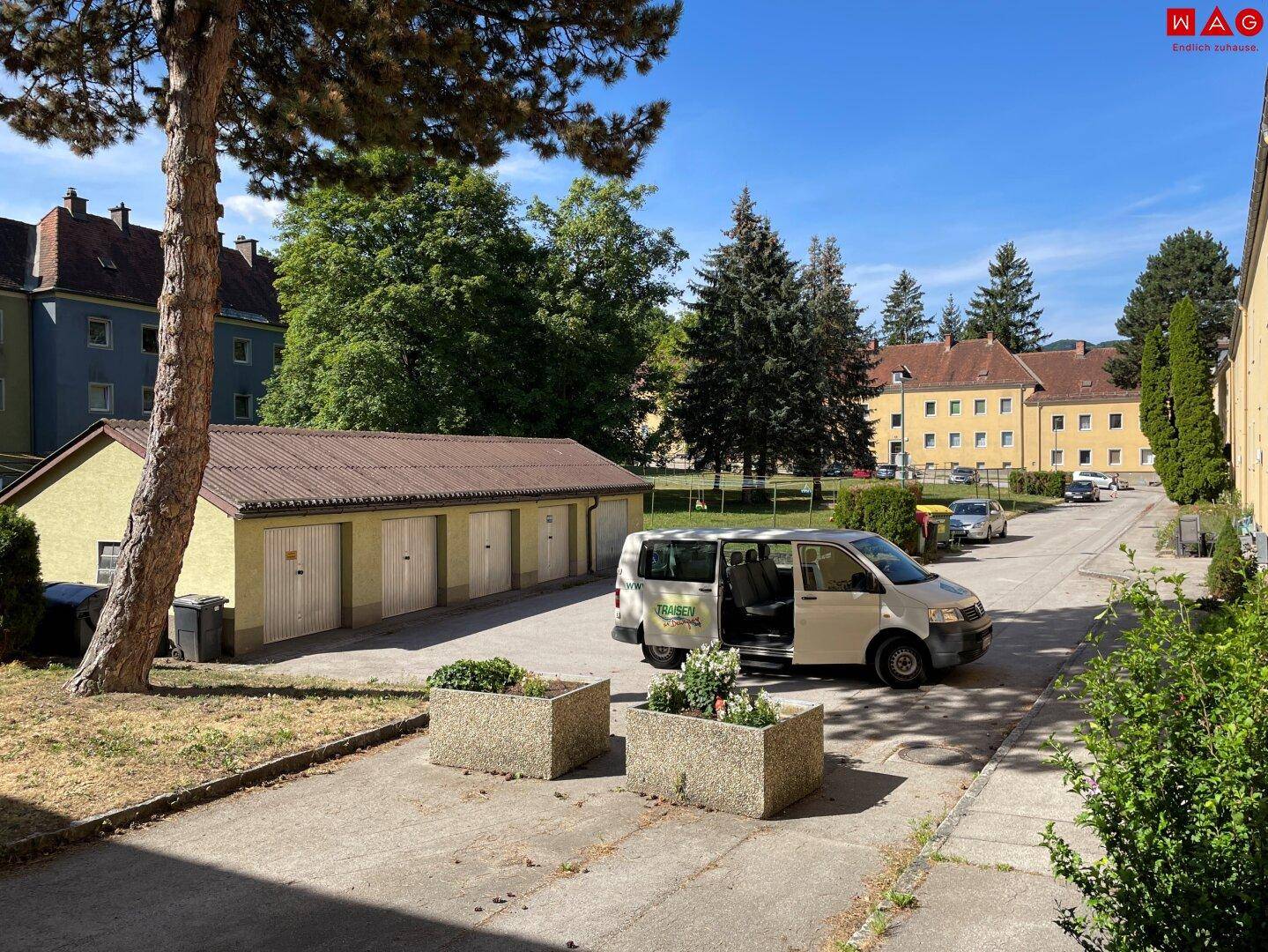 Reihe von Garagen und geparkten Fahrzeugen vor weiteren Wohngebäuden der Anlage.