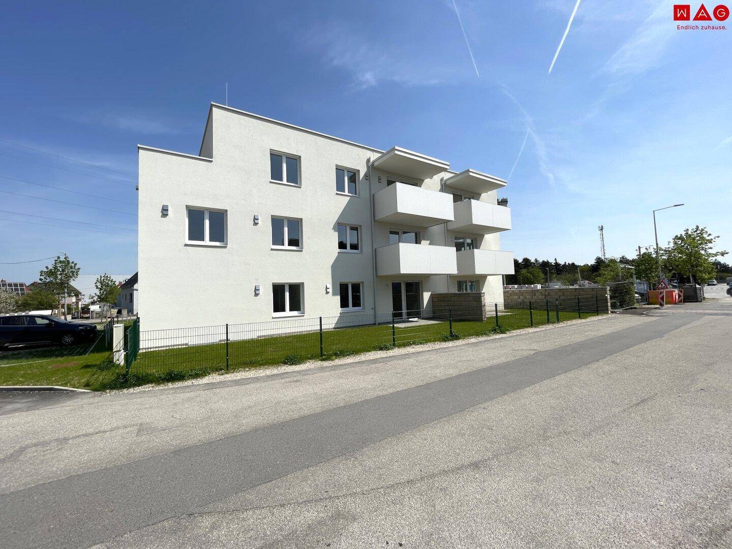 Außenansicht des modernen Wohngebäudes mit Balkonen und umliegender Straße.