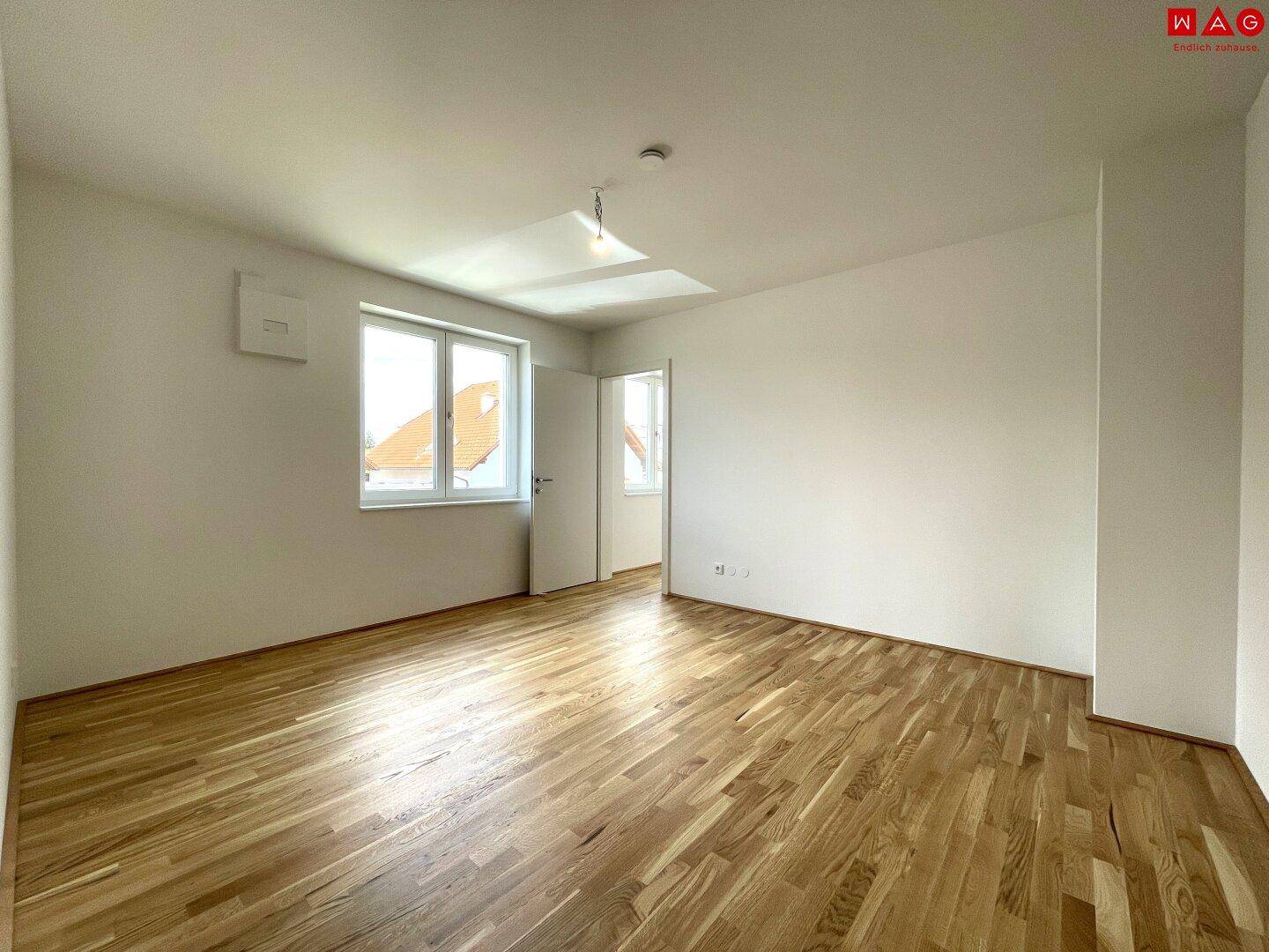 Geräumiges Schlafzimmer mit hellem Holzboden und großen Fenstern für viel Tageslicht.