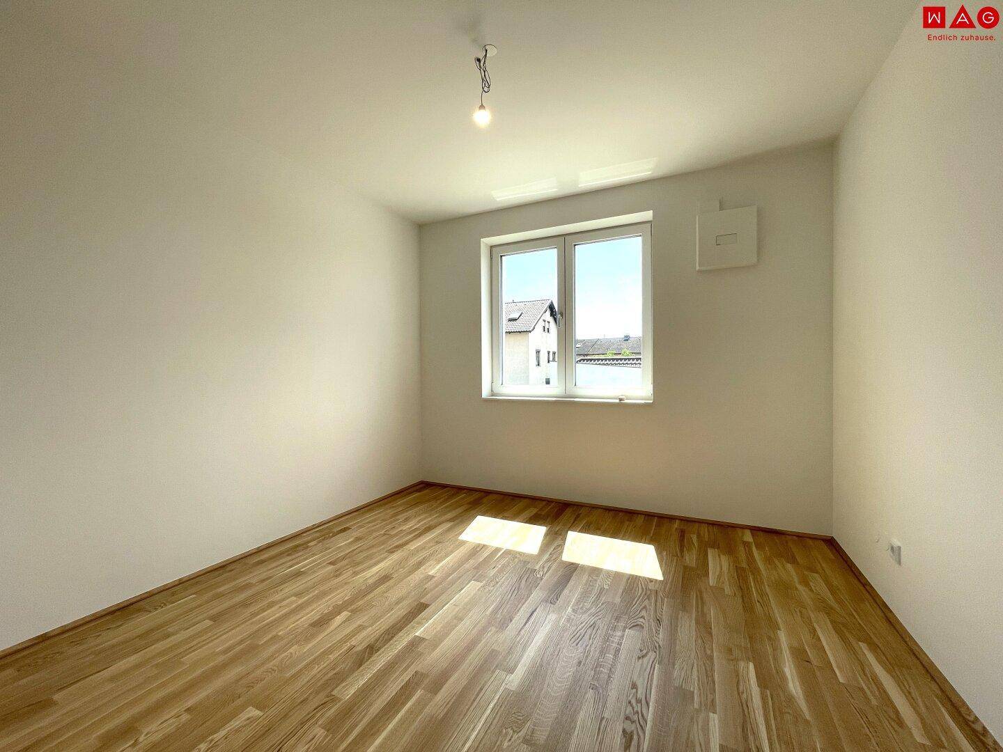 Helles Kinderzimmer mit Holzboden und großem Fenster, ideal für individuelle Gestaltung.