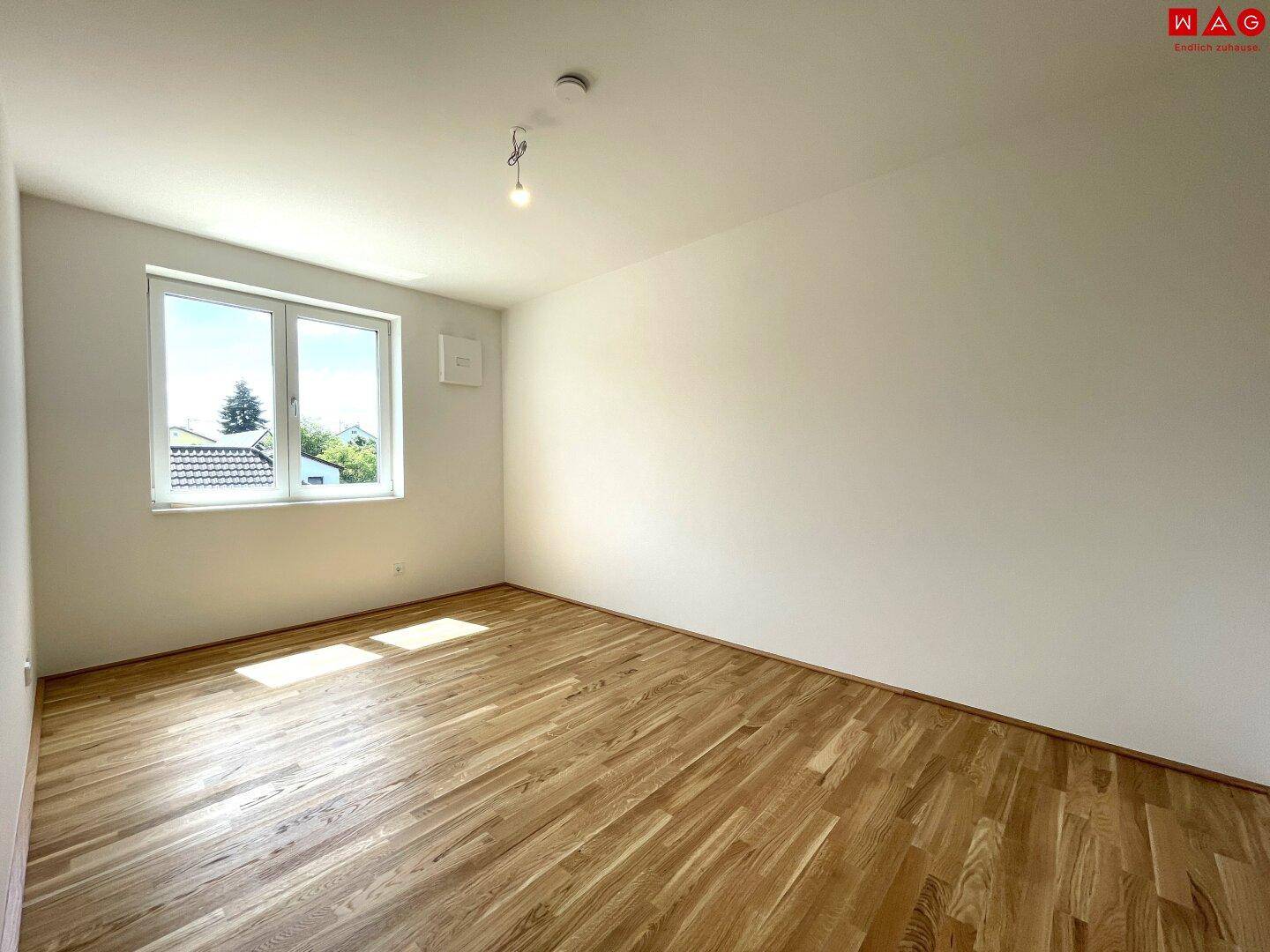 Geräumiges Schlafzimmer mit hellem Holzboden und großen Fenstern, die viel Licht spenden.