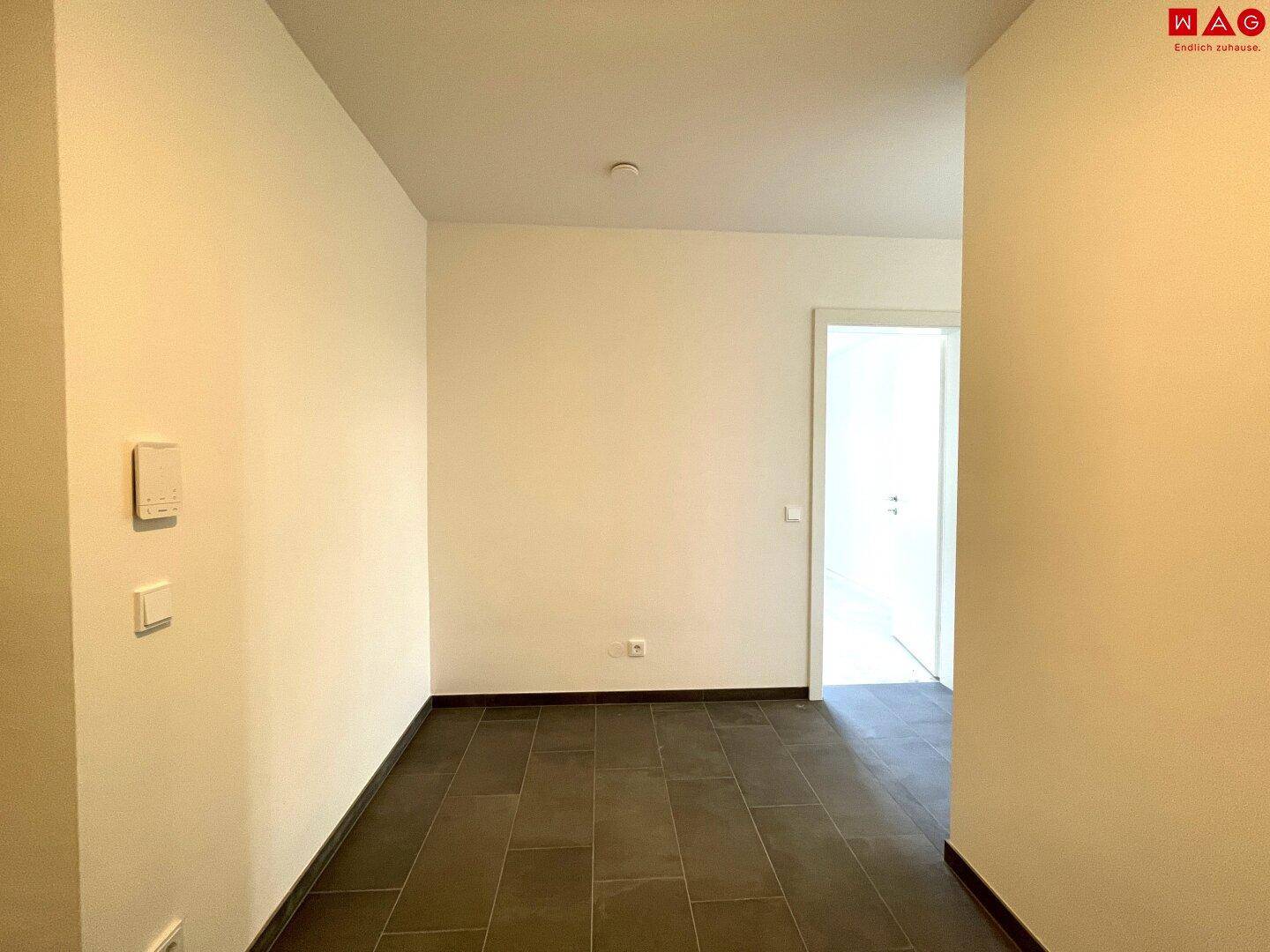 Heller Flur mit Fliesenboden und weißen Wänden, bietet Zugang zu weiteren Räumen.