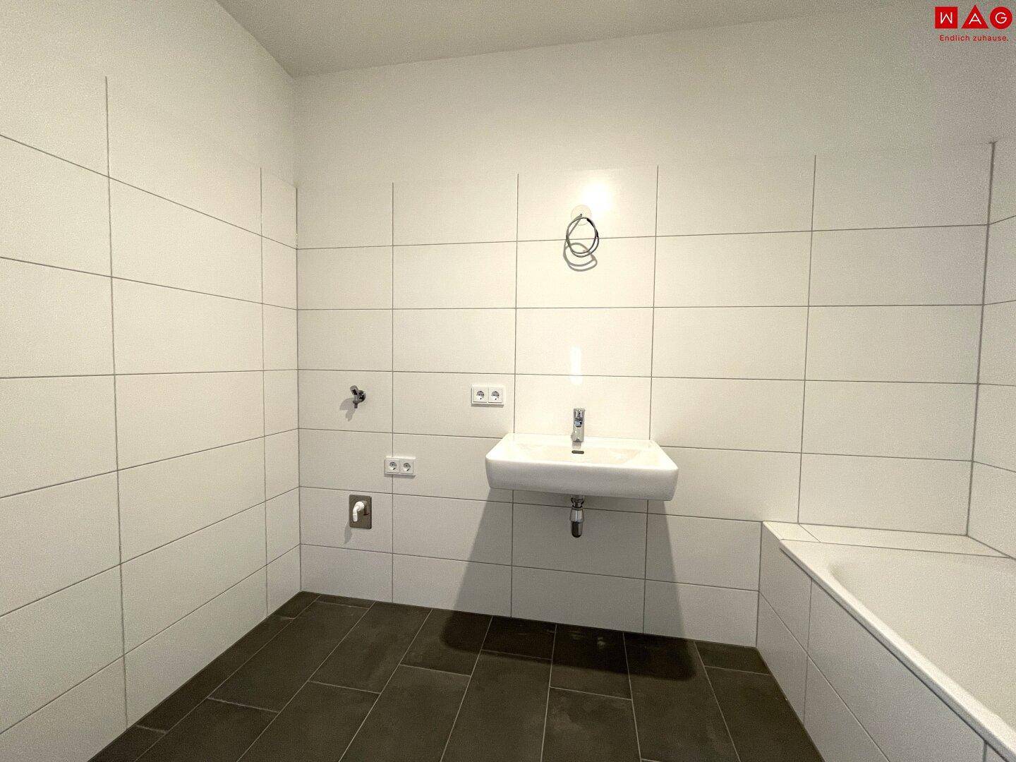 Helles Badezimmer mit Fliesenboden und Badewanne, bereit für die Installation der Möbel.