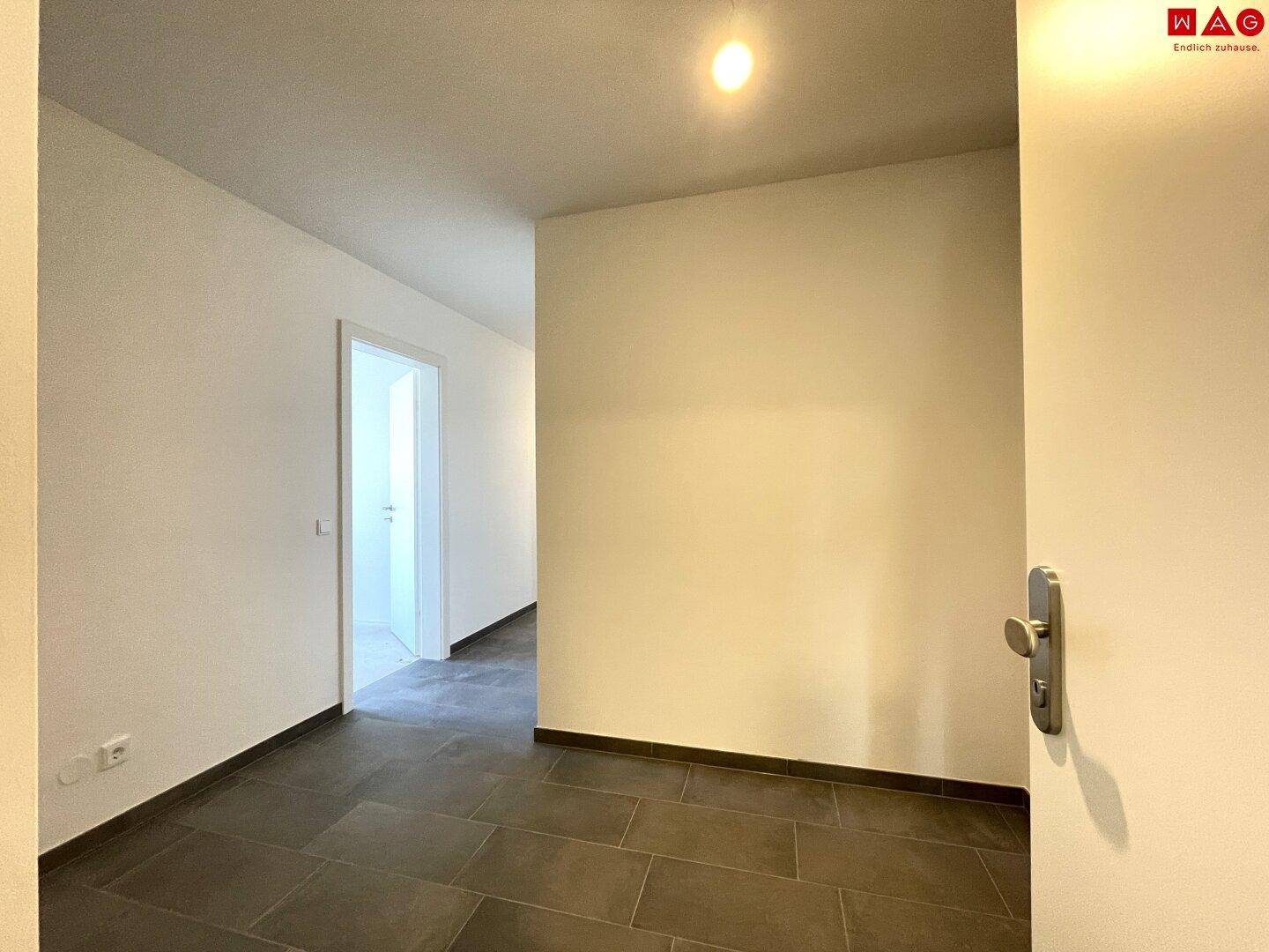Heller Eingangsbereich mit Fliesenboden, der zu den weiteren Räumen der Wohnung führt.