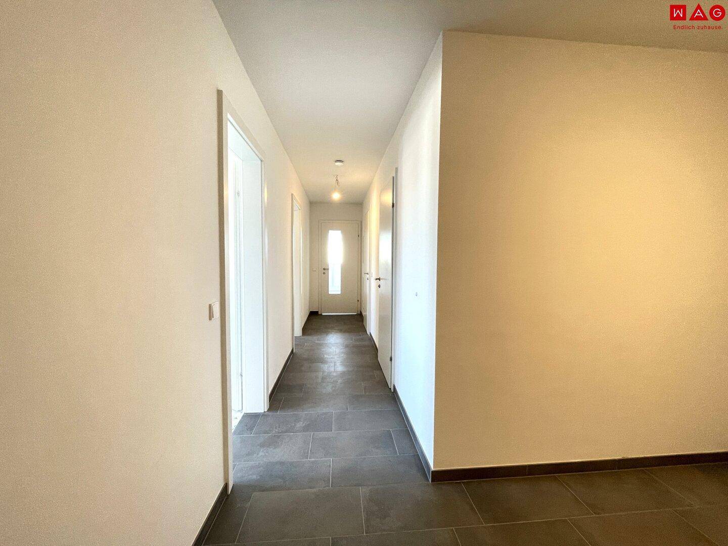 Langer, heller Flur mit Fliesenboden, der die verschiedenen Bereiche der Wohnung verbindet.