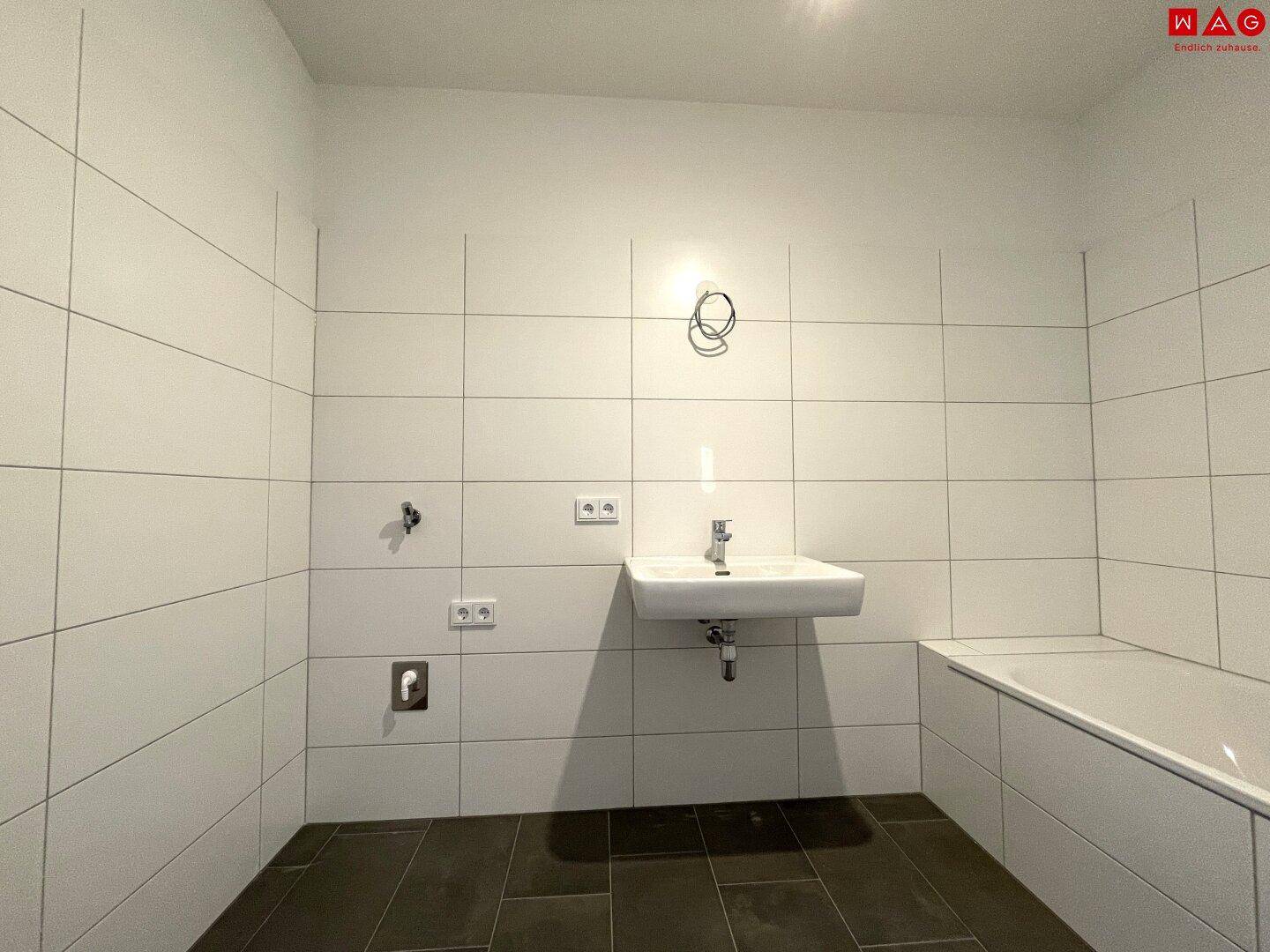 Helles Badezimmer mit Badewanne und Waschbecken, bereit für die individuelle Gestaltung.