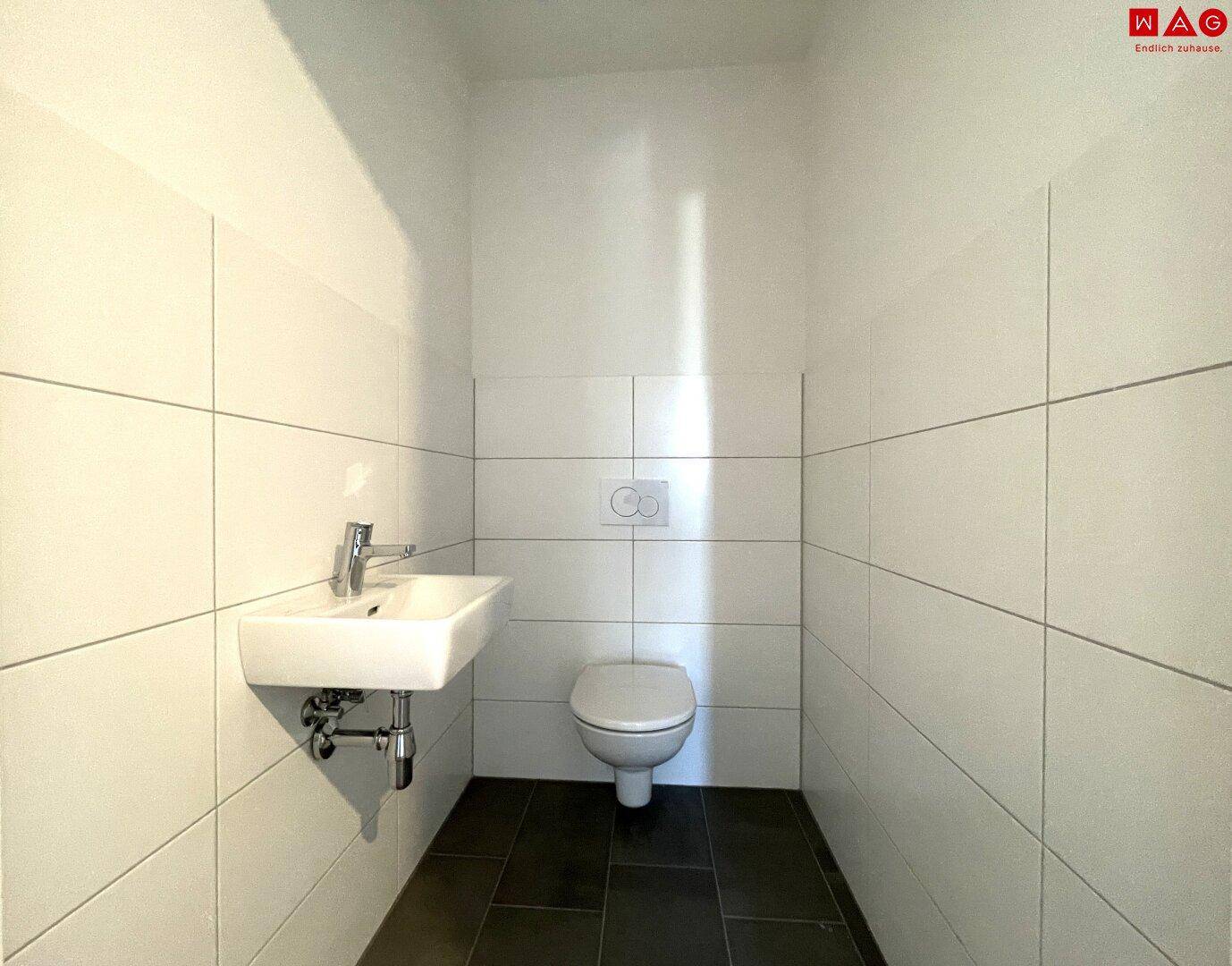 Funktionales Gäste-WC mit Wand-WC und Waschbecken, ideal für Besucher.