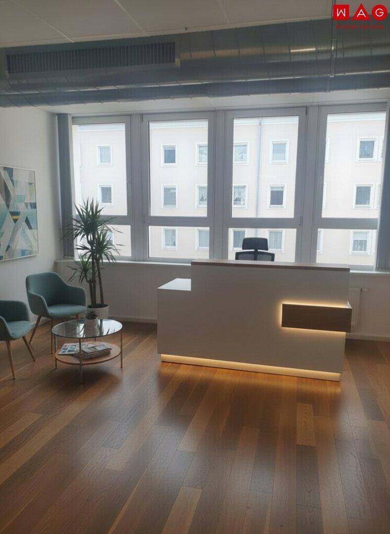 Moderner Empfangsbereich mit beleuchteter Theke, Holzboden und Sitzgelegenheiten.