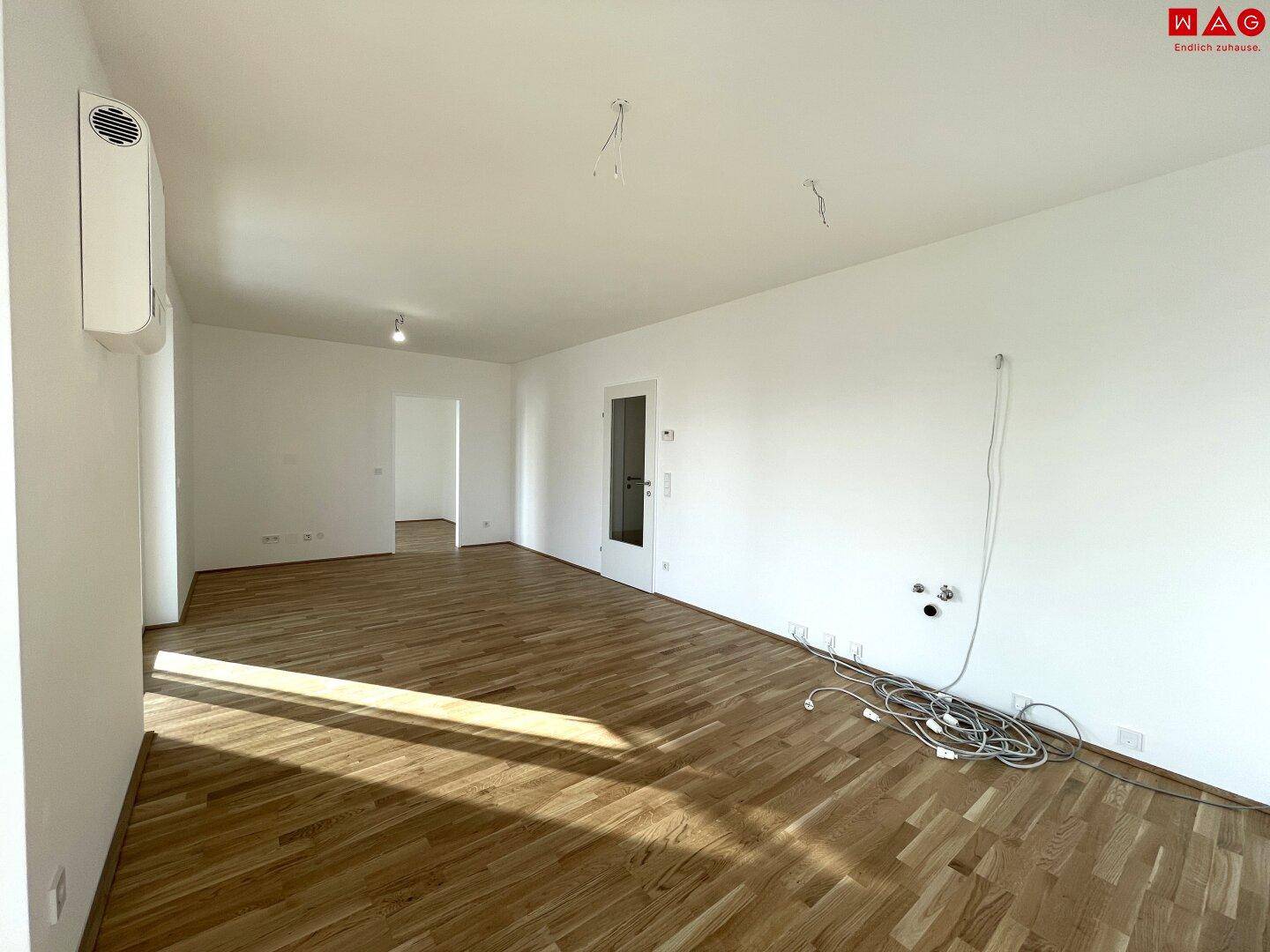 Heller Wohnraum mit Parkettboden, Klimaanlage und vorbereiteten Anschlüssen.
