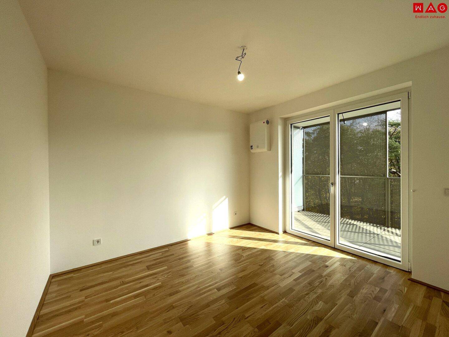 Helles Schlafzimmer mit Parkettboden und direktem Zugang zu einem privaten Balkon.