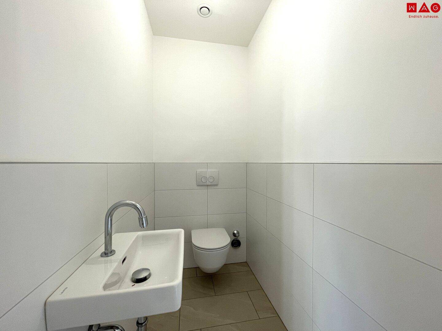 Kleines, modernes Gäste-WC mit wandhängender Toilette und Waschbecken.