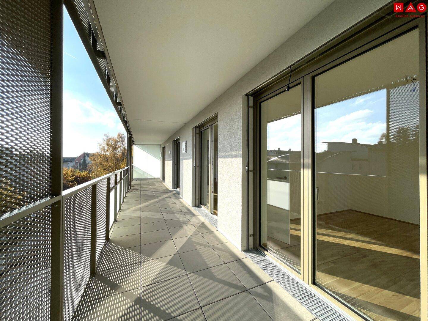 Geräumiger Balkon mit Fliesenboden und mehreren Zugängen zu den Innenräumen.