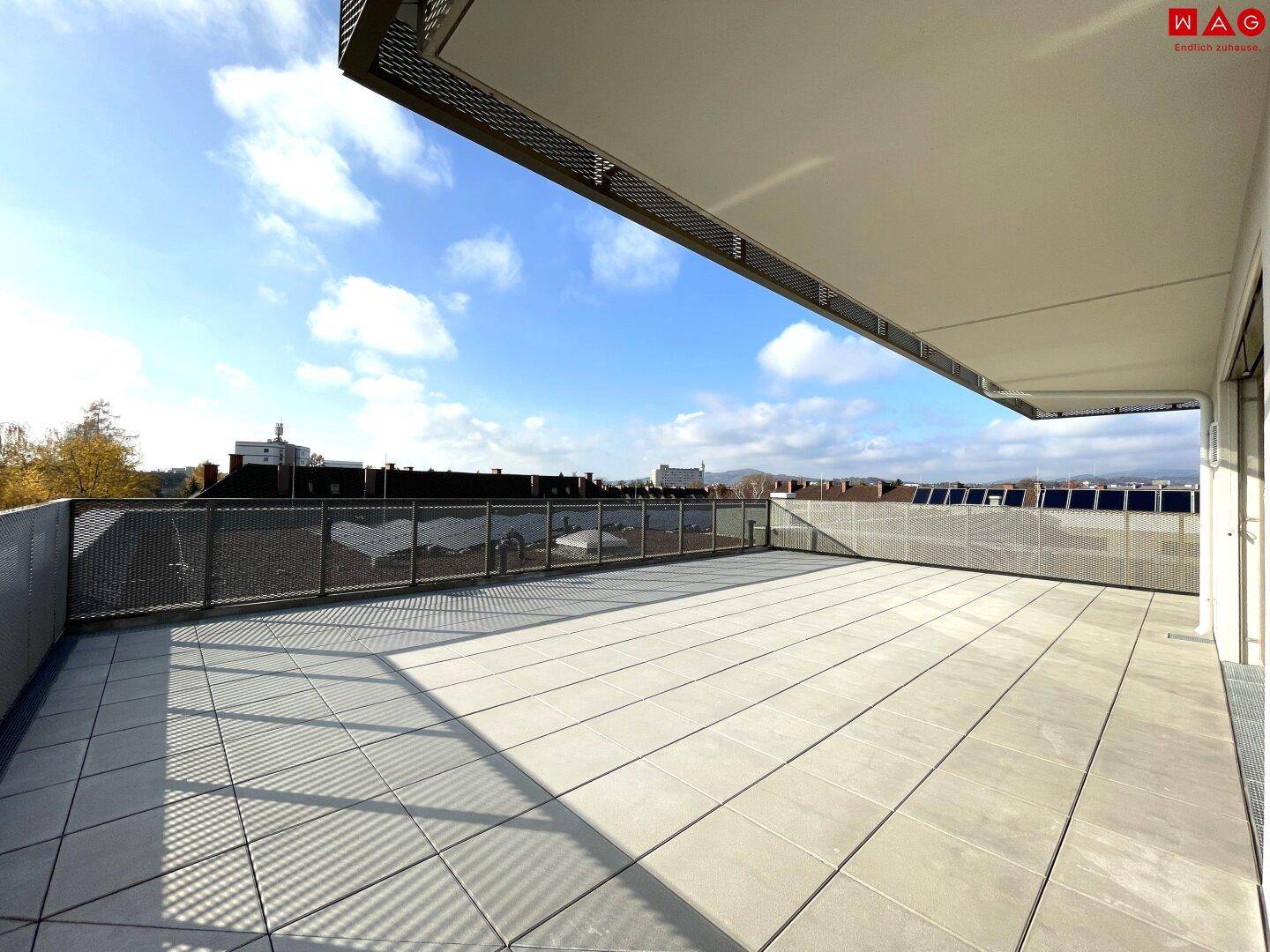 Weitläufige, unmöblierte Dachterrasse mit Fliesenboden und weitem Blick über die Umgebung.