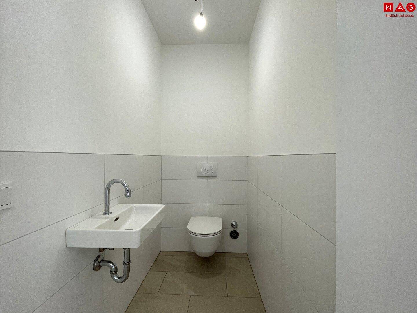 Helles Gäste-WC mit wandhängender Toilette und Waschbecken, bereit für die Endmontage.