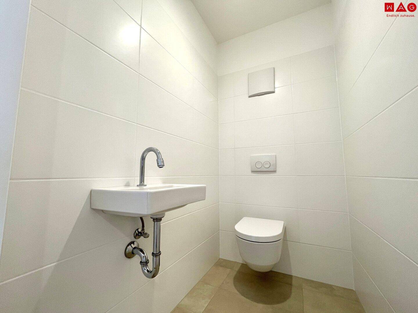 Helles Gäste-WC mit wandhängendem WC und Waschbecken, gefliest und funktional.