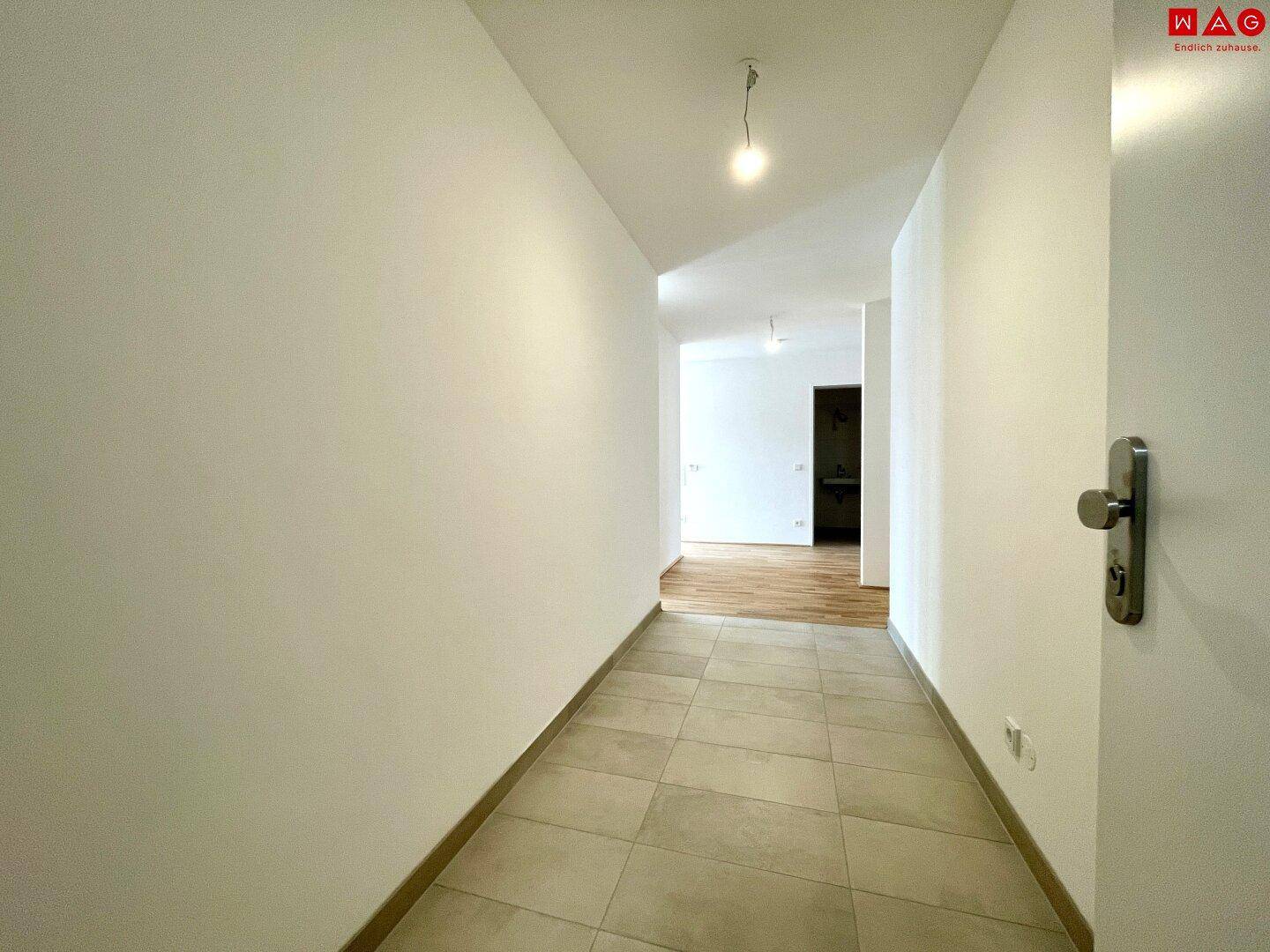Schmaler Flur mit Fliesenboden, der zu weiteren Räumen der Wohnung führt.
