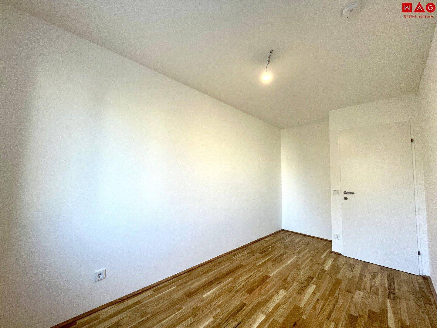 Leeres Schlafzimmer mit Holzboden und weiß gestrichenen Wänden, bereit zur Einrichtung.