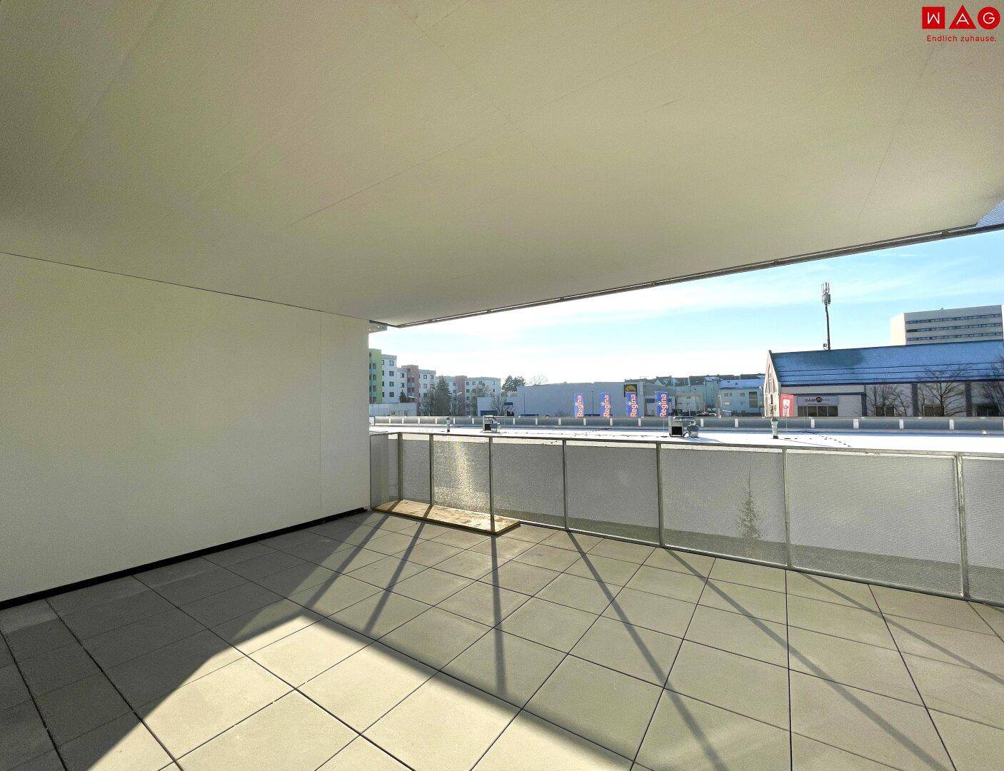Überdachte Terrasse mit Fliesenboden und weitem Blick auf die städtische Umgebung.