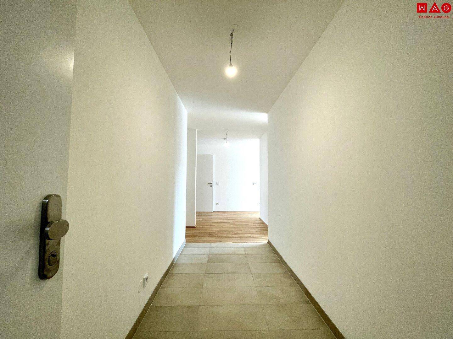 Leerer, heller Flur mit Fliesenboden, der zu den weiteren Räumen der Wohnung führt.