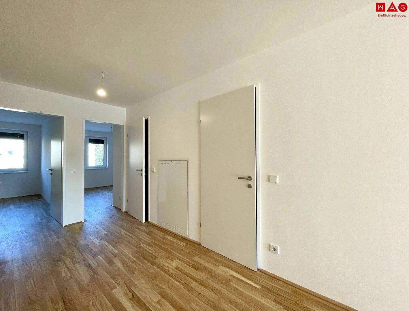 Heller Flur mit Holzboden und mehreren Türen, die zu den angrenzenden Zimmern führen.
