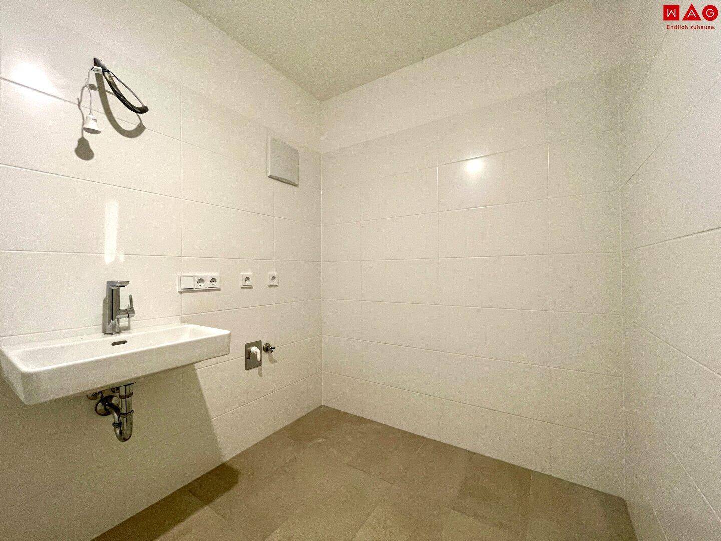 Funktionaler Raum mit Waschbecken und Anschlüssen, ideal als Hauswirtschaftsraum.