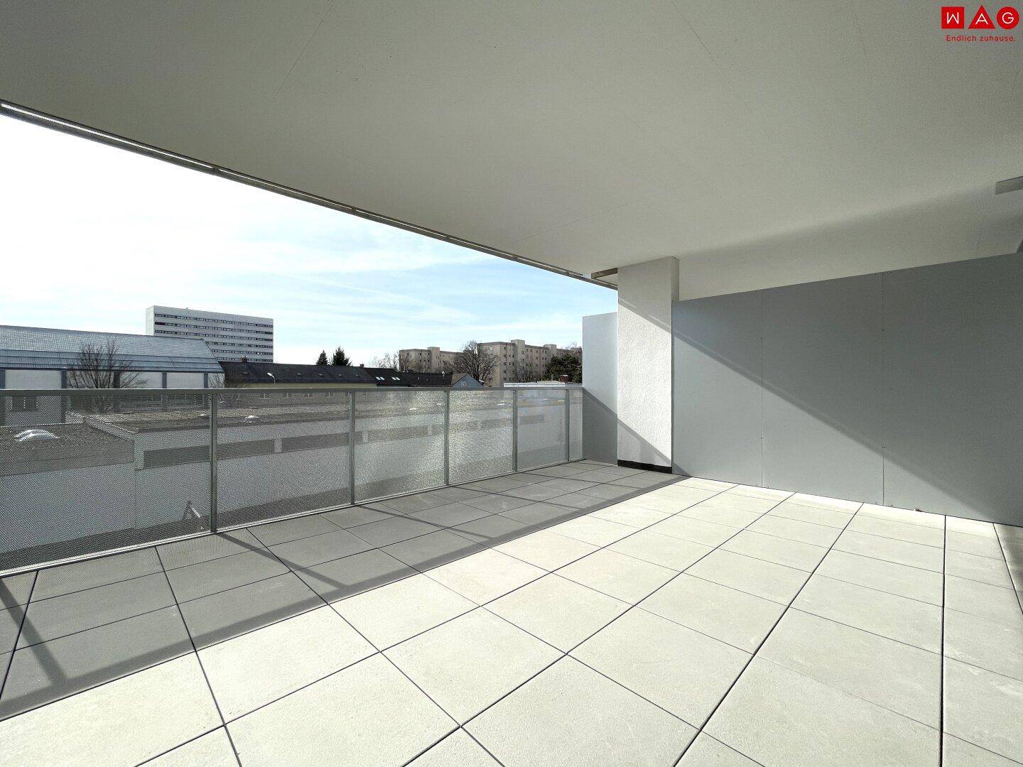 Weitläufige Terrasse mit Fliesenboden und offenem Blick auf die städtische Umgebung.