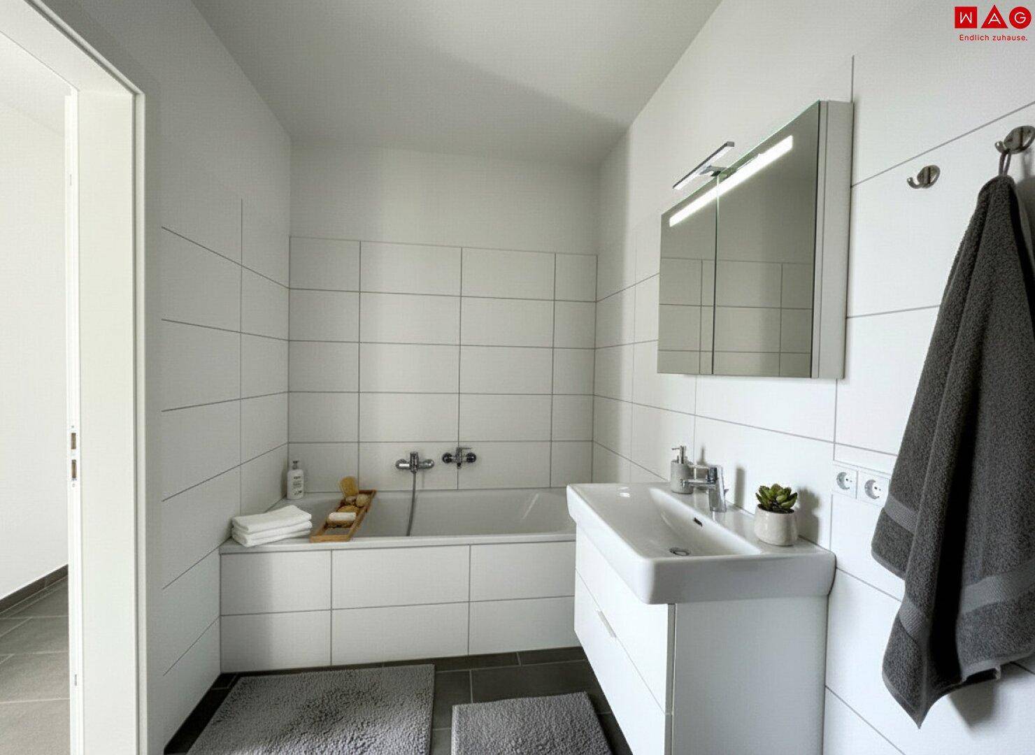 Modernes Badezimmer mit Badewanne, Waschbecken, Spiegelschrank und weißen Wandfliesen.