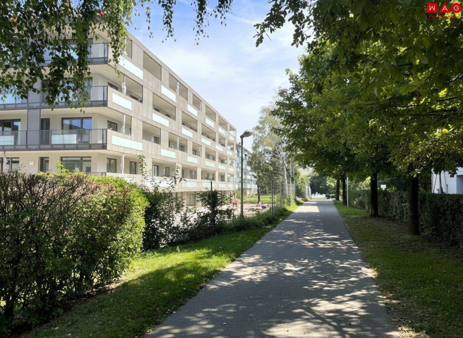 Moderne Wohnanlage mit Balkonen, umgeben von Grünflächen und Bäumen.