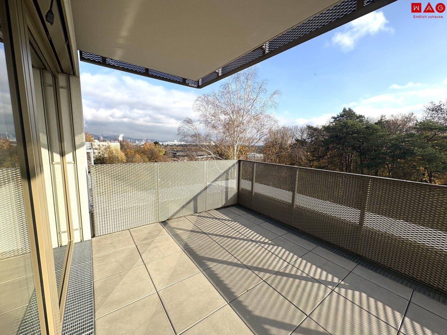 Heller Balkon mit Fliesenboden und Blick ins Grüne, ideal für sonnige Tage.