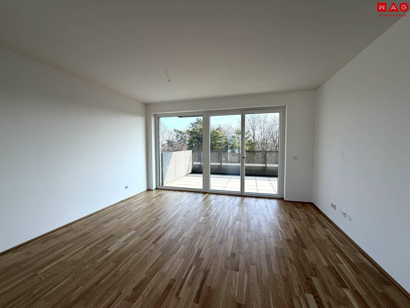 Helles Wohnzimmer mit Holzboden und großem Terrassenzugang, bietet viel Tageslicht.
