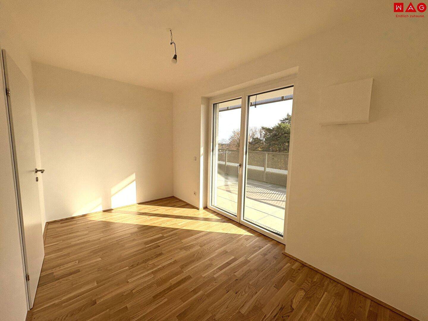 Schlafzimmer mit Holzboden und Terrassenzugang, bietet viel natürliches Licht.